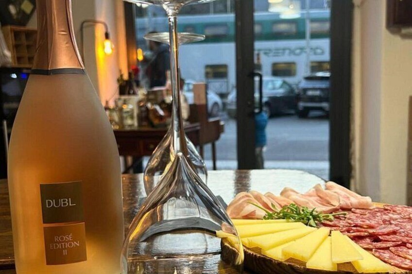 En flaske Dubl Rosé Edition II, et glas og en skærebræt med pålæg og ost. 2