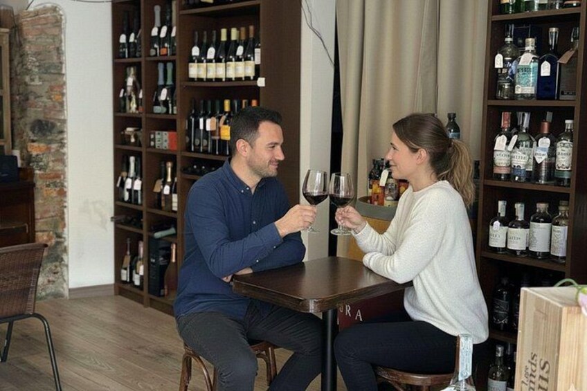 Dos personas sentadas a una mesa en una habitación con estanterías llenas de botellas. 3