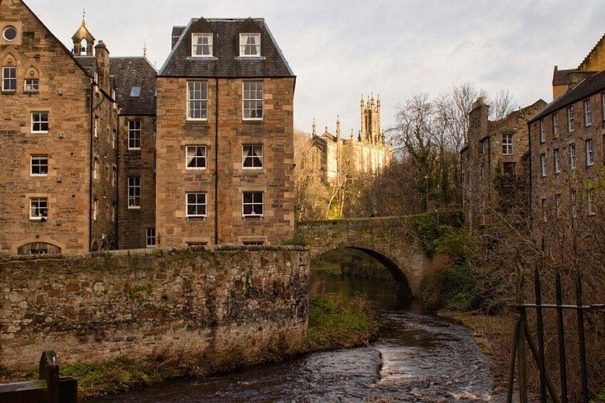 A stone bridge over a river, historic buildings, and a castle in the background. 2