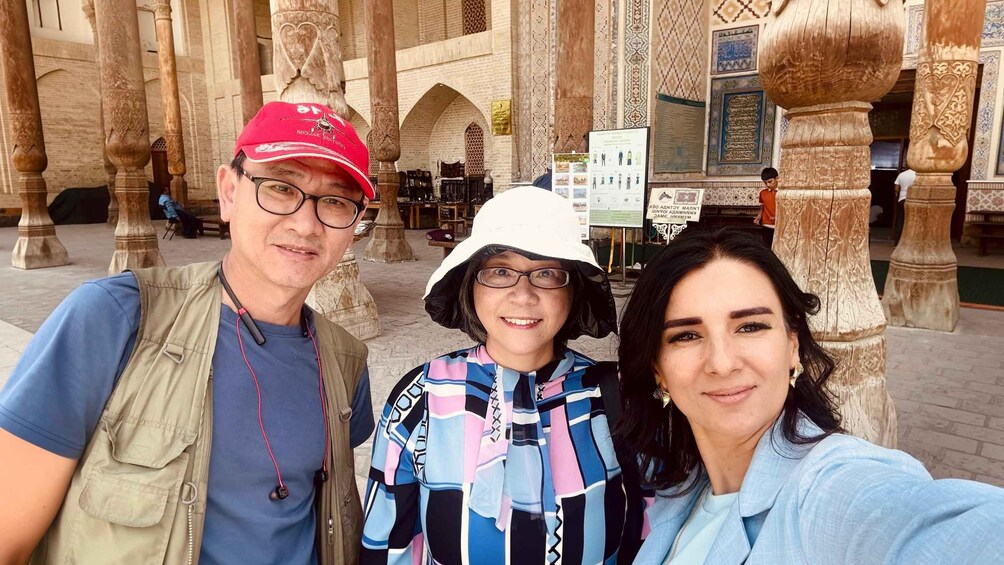 Three people taking a selfie in front of a historic building with intricate carvings and arches. 4