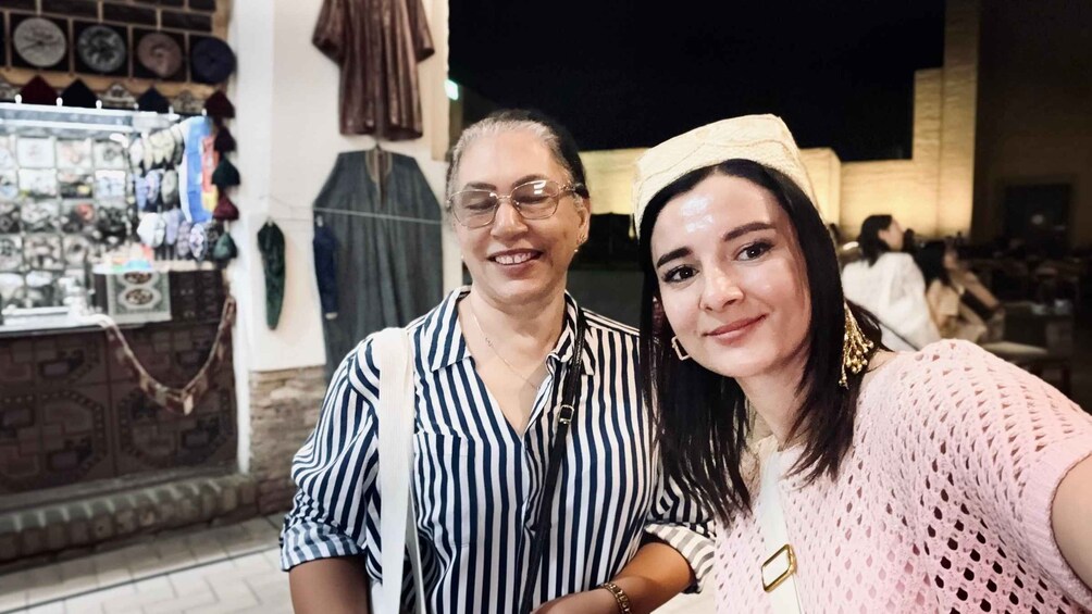 Two people taking a selfie in an outdoor setting with a shop in the background. 5