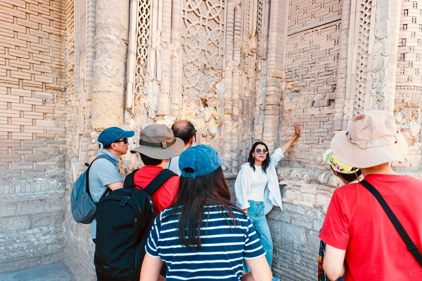 Tourists examining ancient brickwork and carvings. 1