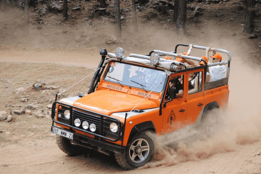 Un véhicule tout-terrain orange traverse un terrain accidenté et poussiéreux. 3