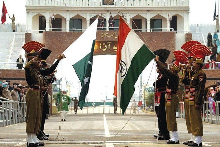 A ceremonial event with individuals in traditional attire holding flags in front of a building with arches. 2