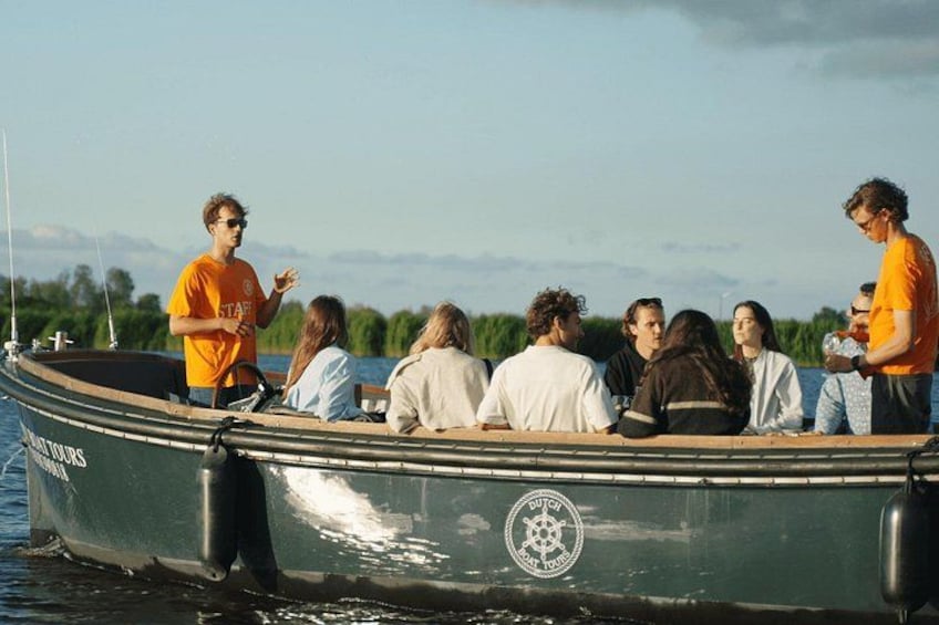 A group of people on a boat with a man standing at the front, possibly giving a tour. 2
