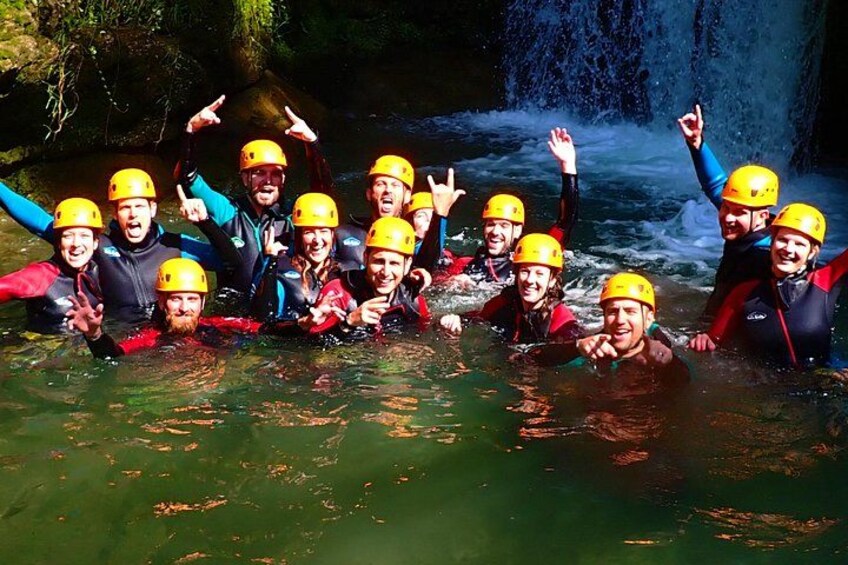 A group of people wearing helmets and life jackets in a river. 2