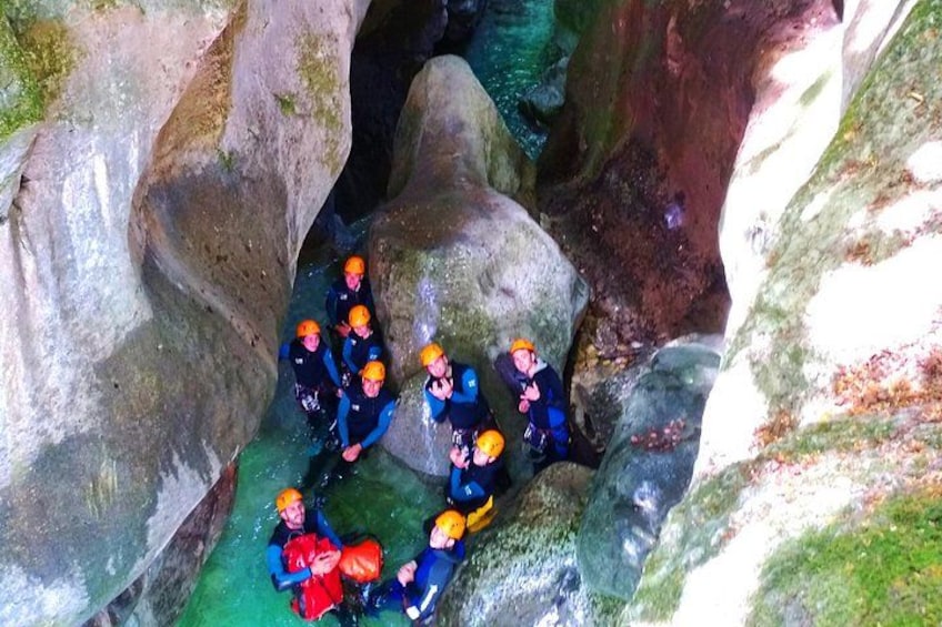 A group of people in helmets and wetsuits in a rocky water environment. 4