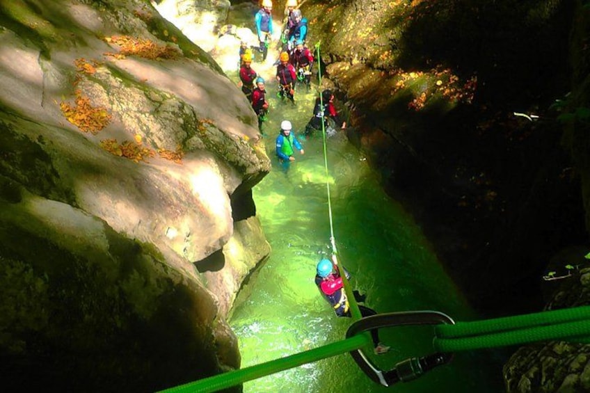 A group of people rappelling down a rocky cliff into a river. 1