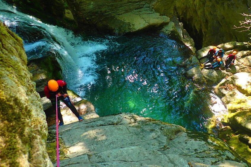 A person rappelling down a rocky cliff into a flowing river. 3