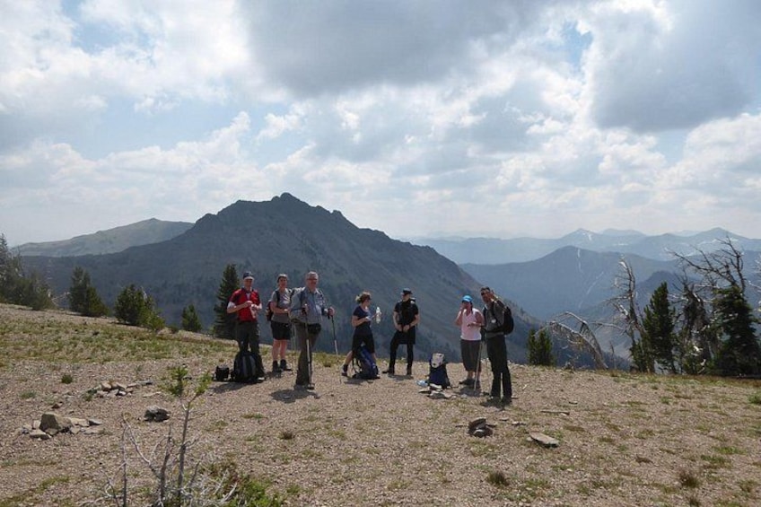 A group of people standing on a mountain ridge with a mountain range in the background. 2