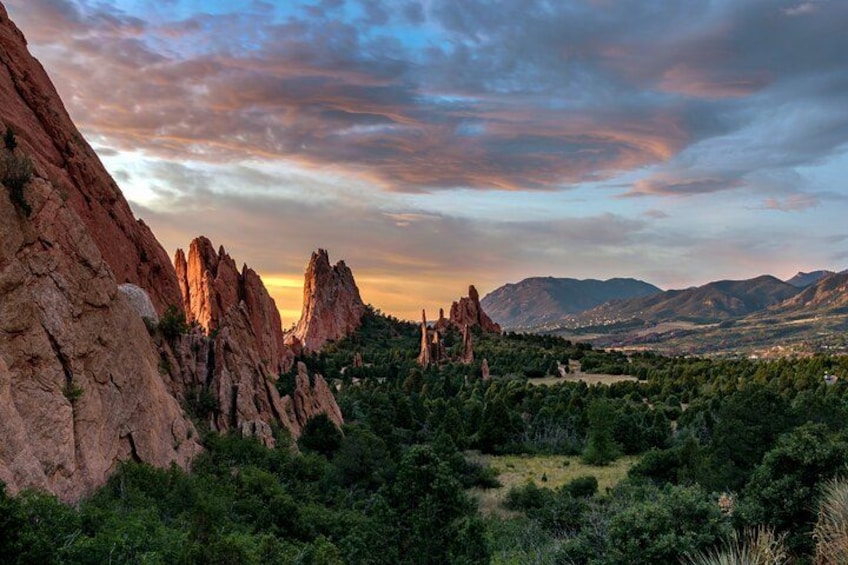Un paisaje montañoso con destacadas formaciones rocosas rojas y un valle cubierto de vegetación. 1
