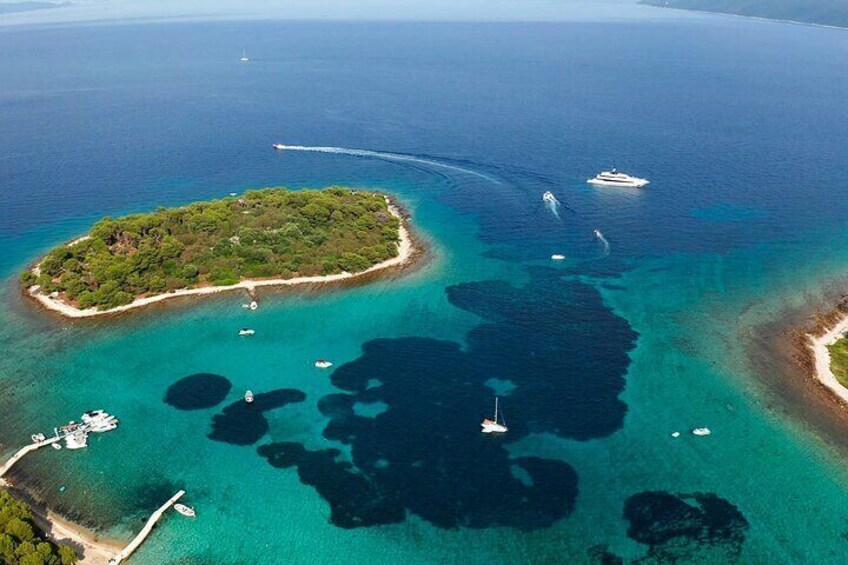An aerial view of a turquoise sea with a small island, clear waters, and a few boats. 5