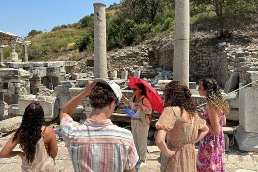 Tourists at an ancient ruin site with columns and stone structures. 1