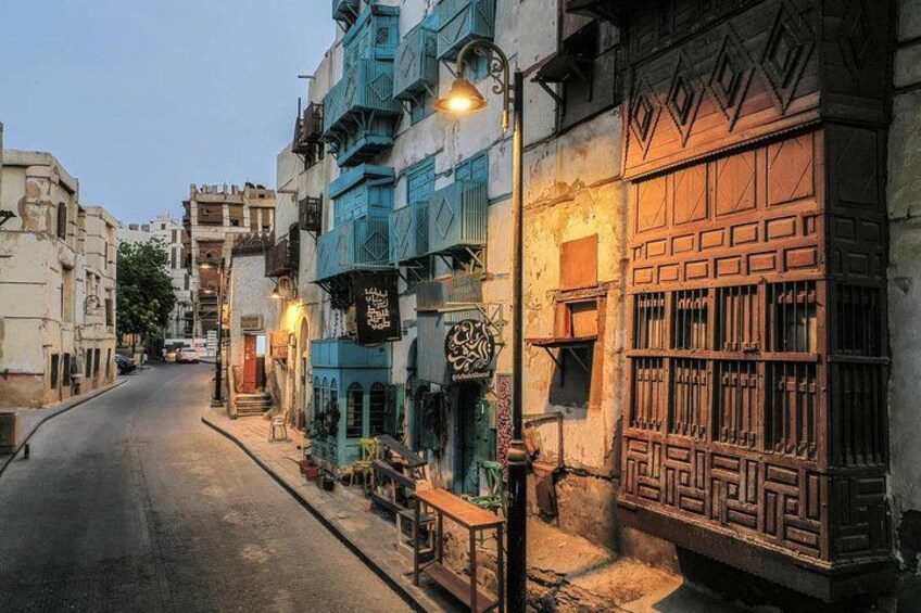 A narrow street lined with traditional buildings, some with blue shutters and intricate wooden doors. 5