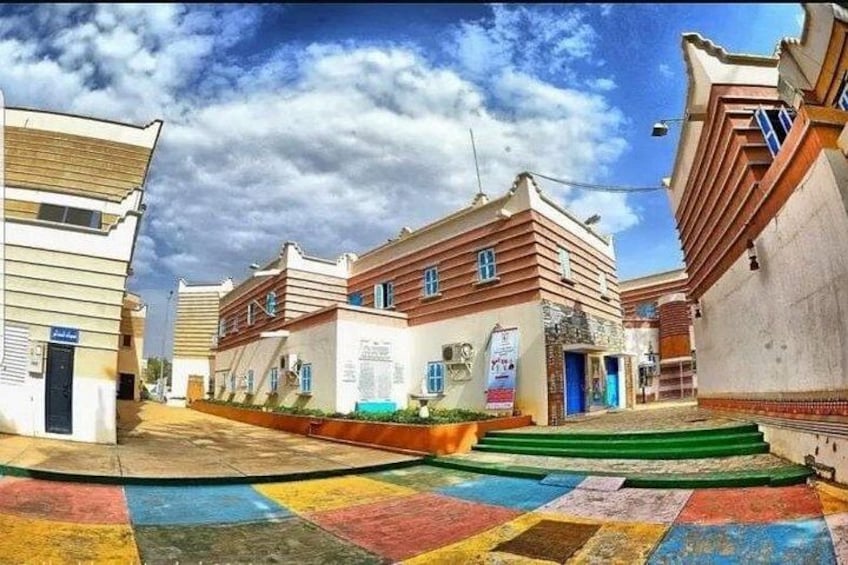 A street with colorful pavement, buildings with sloped roofs, and a clear sky. 2