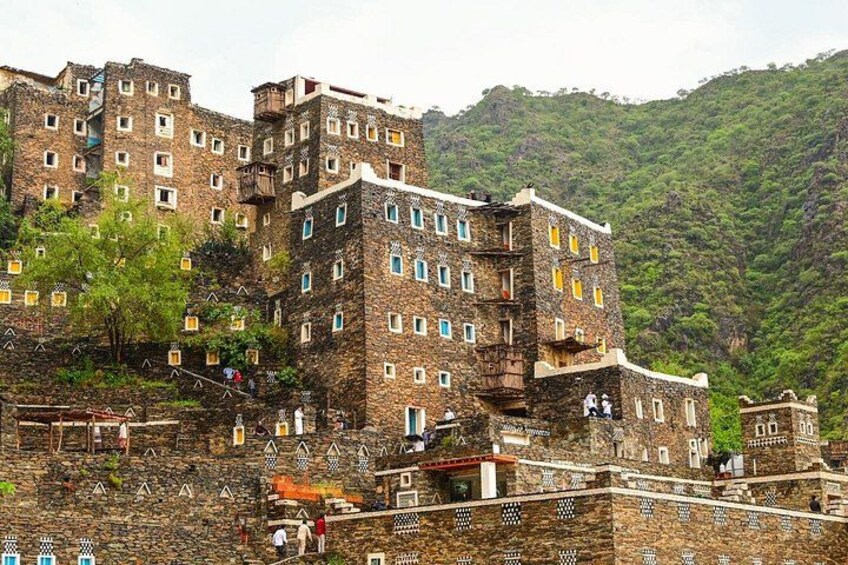 A multi-story building with a stone facade, set against a mountainous backdrop. 5