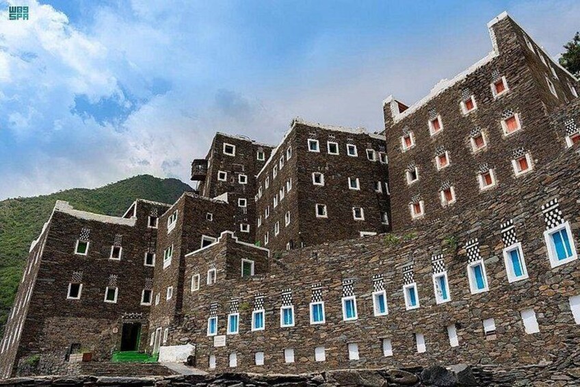 A large stone building with multiple windows and a green door. 4