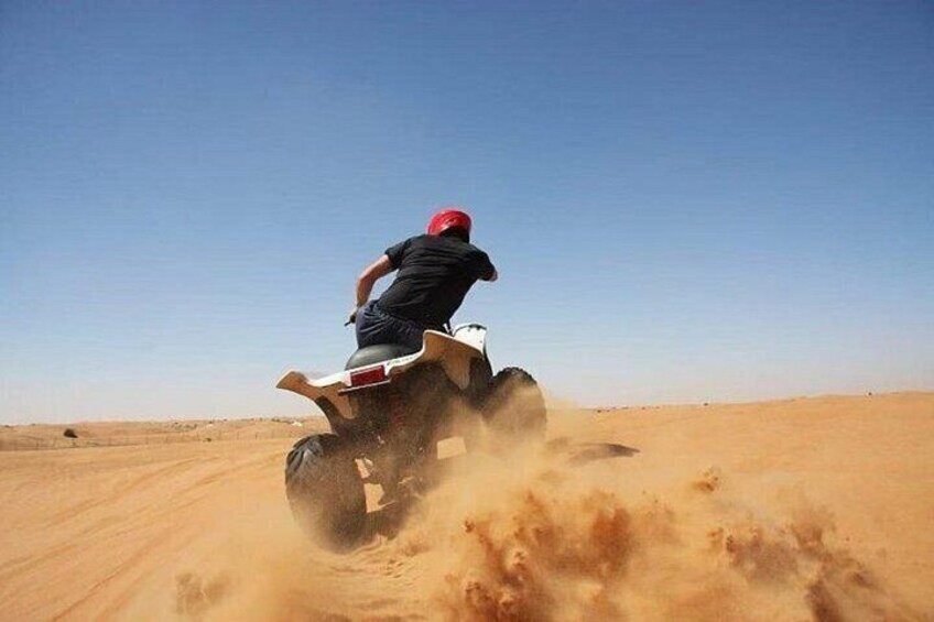 Een persoon rijdt een quad op in een woestijn. 1