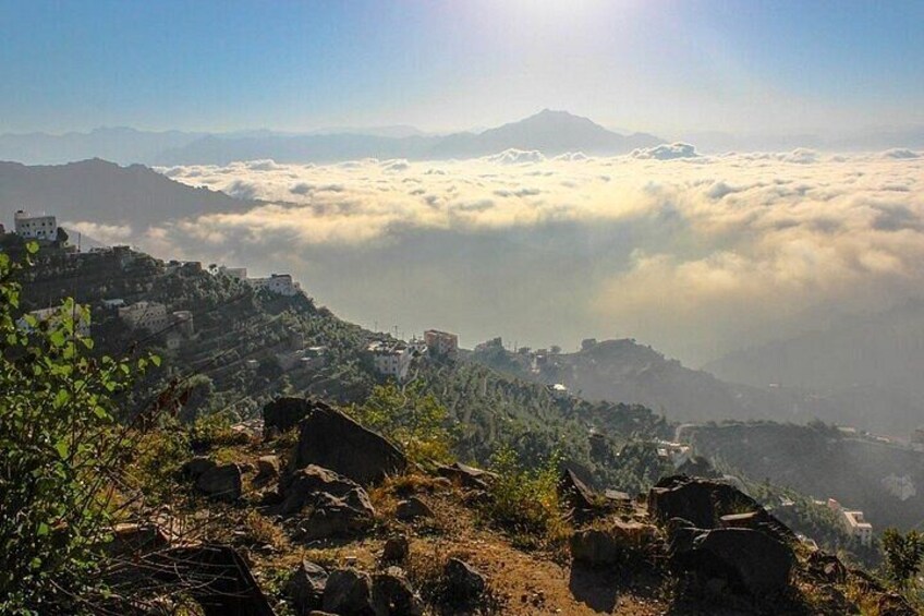 A mountainous landscape with buildings, clouds, and a mountain in the distance. 2
