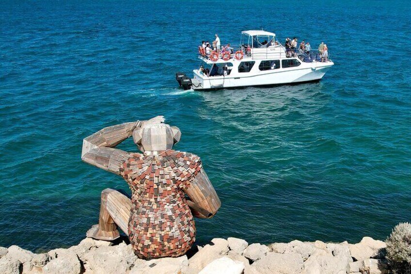 A white boat with people on it, a rocky shore, and a mosaic sculpture. 5