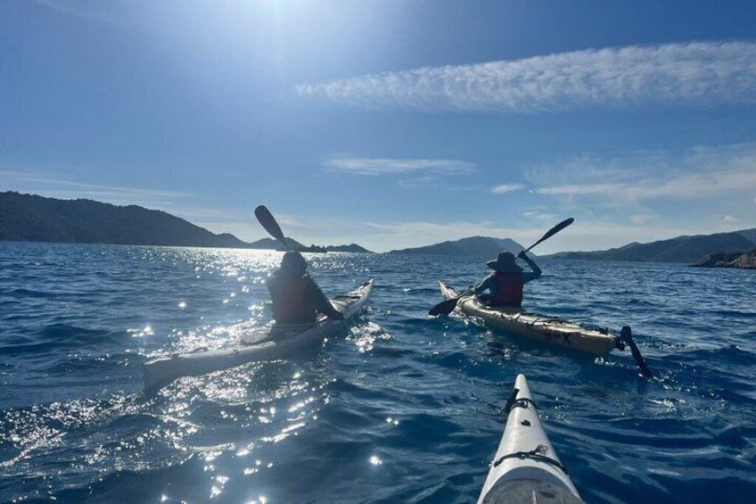 Two kayaks on a calm sea with a clear sky and distant land. 1