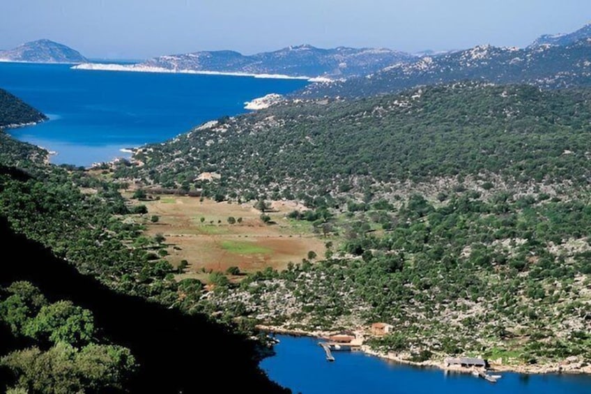 A coastal landscape with a clear blue sea, a green valley, and a small settlement near the water. 2
