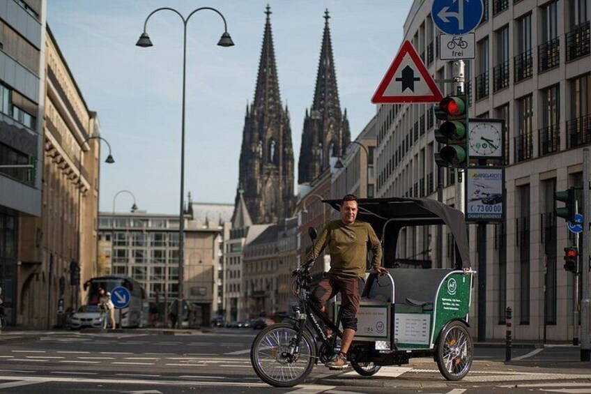 Een fietser met aanhangwagen, verkeerslicht en een kerktoren op de achtergrond. 3
