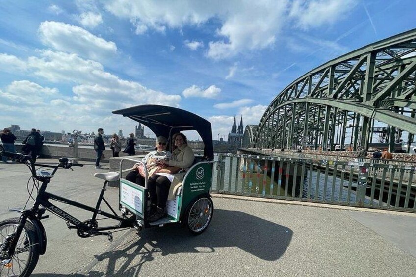Een groene bagagewagen met een luifel, een fiets en een voetgangersbrug. 1