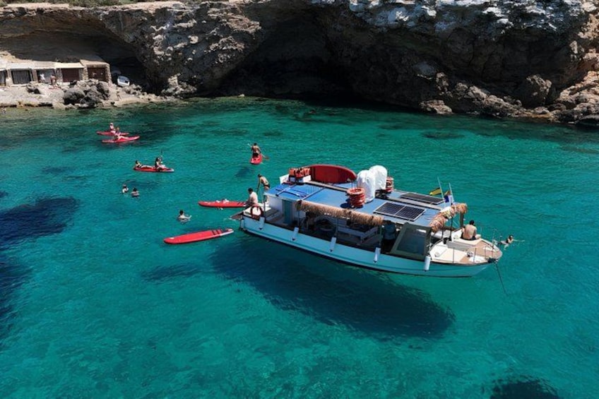 A boat with people on a clear turquoise sea, surrounded by rocky cliffs. 1