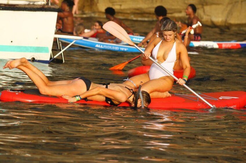 People on a raft in a body of water, with a boat and other rafts in the background. 5