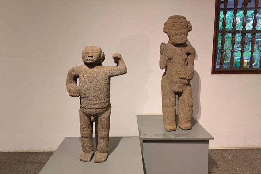 Två statyer av sten, placerade på piedestaler i en museimiljö. 4
