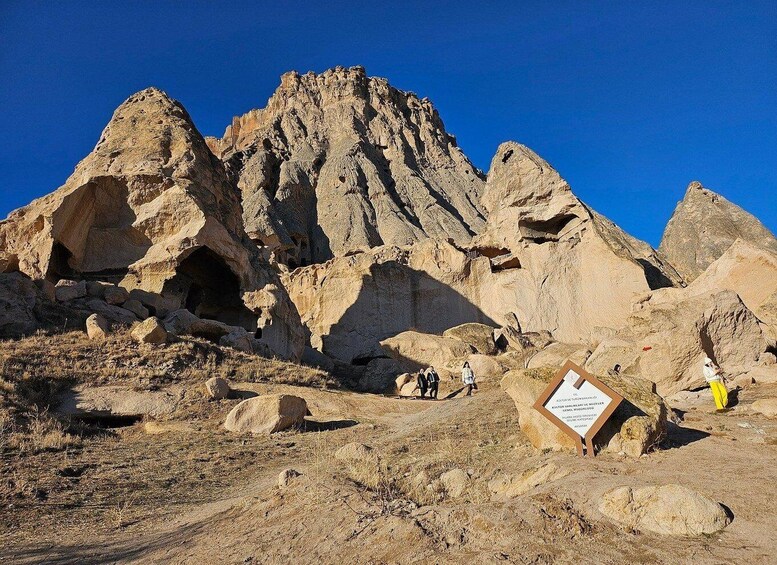 A rocky landscape with a prominent mountain peak and a signboard. 5