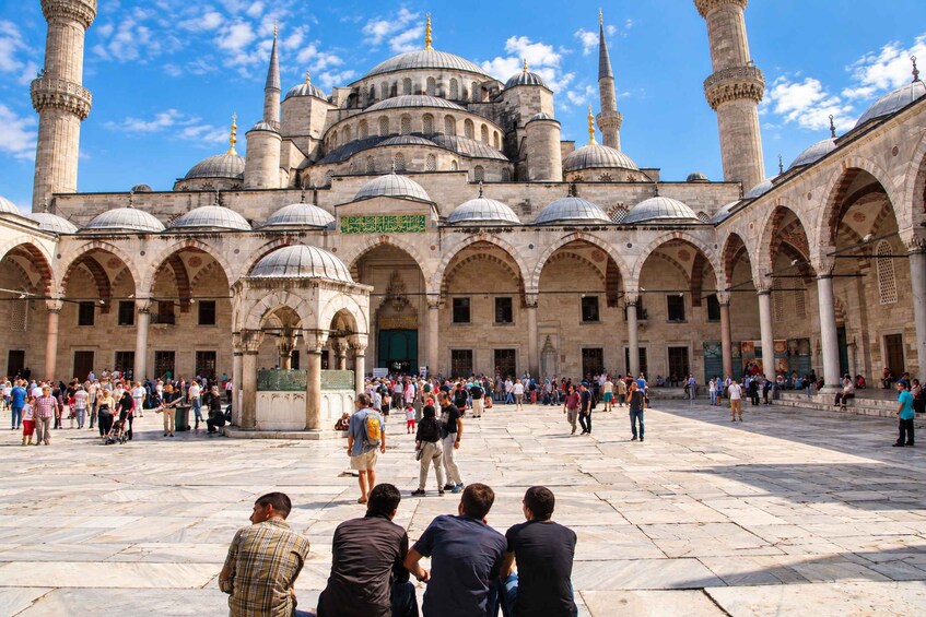A historic building with multiple domes and minarets, surrounded by a courtyard with people. 5
