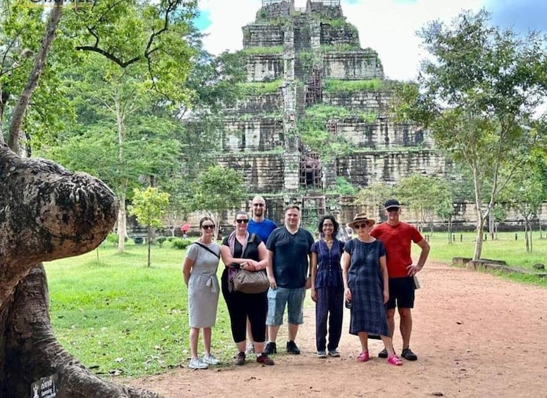 A group of people standing in front of a large ancient temple complex surrounded by trees. 1