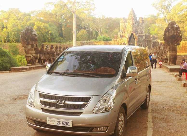 A silver van parked in front of a temple with stone carvings. 3