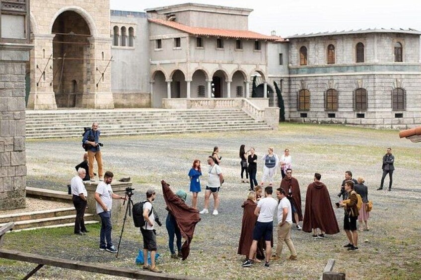 A group of people in a courtyard with stone buildings and arches. 3