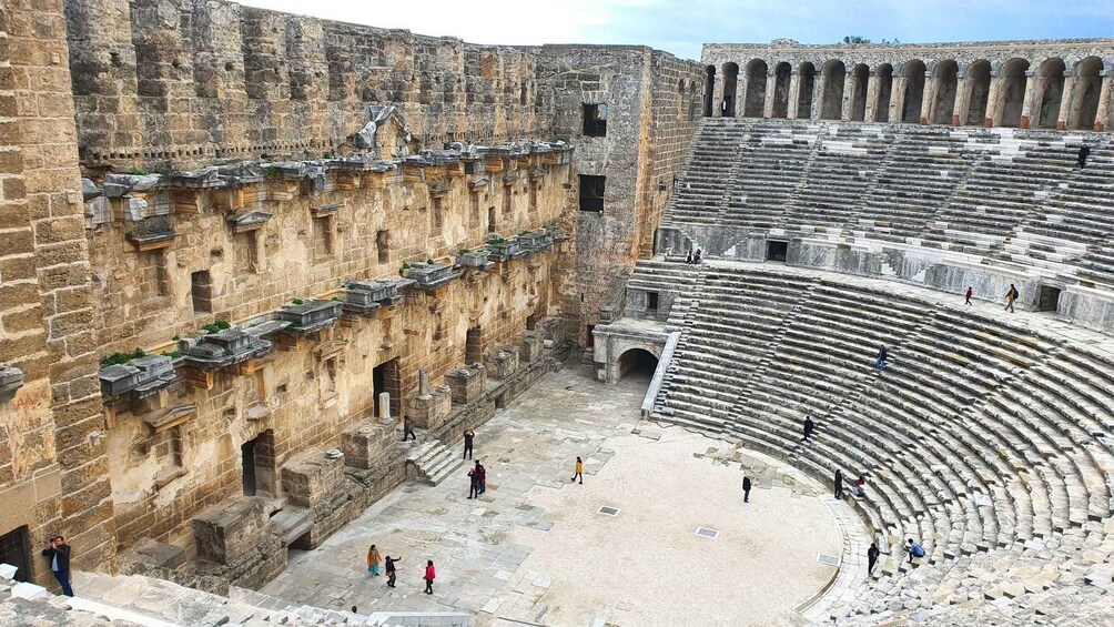 An ancient amphitheater with stone steps and a central stage. 3