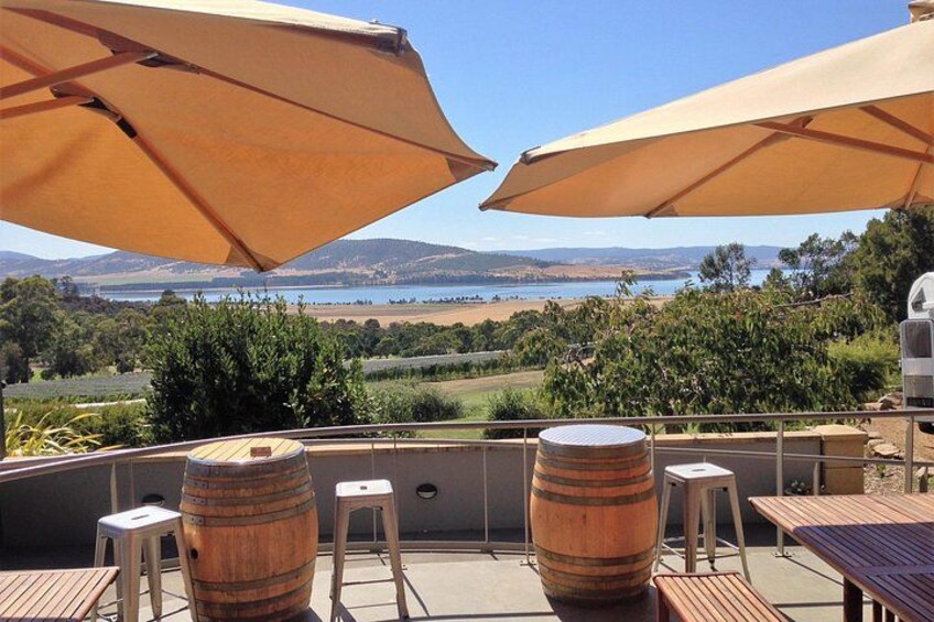 Un patio con barriles de madera, dos taburetes y grandes sombrillas con vistas a un paisaje pintoresco. 2