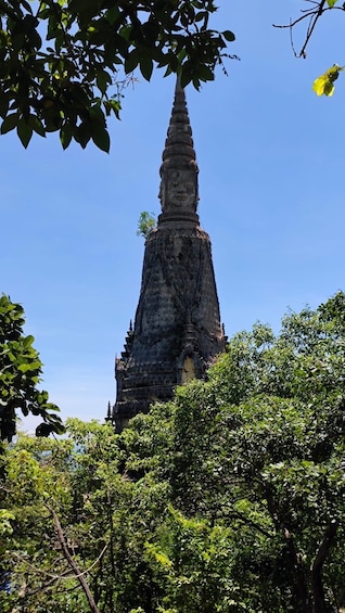 A tall, ancient stone structure with a pointed top, surrounded by lush green foliage. 3