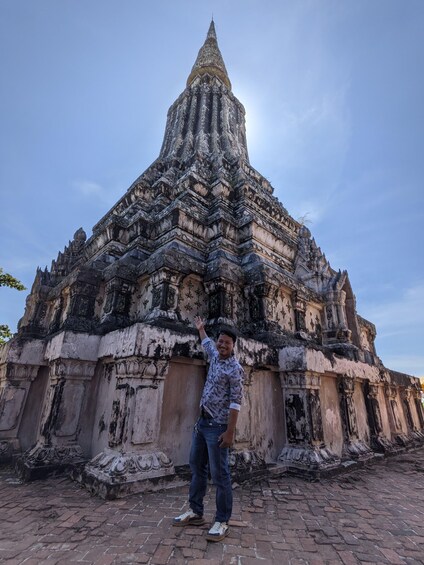 A person standing in front of an ancient temple with intricate carvings and a pointed spire. 1