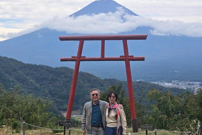 Ein Paar steht vor einem roten Torii-Tor, im Hintergrund ist ein Berg zu sehen. 3