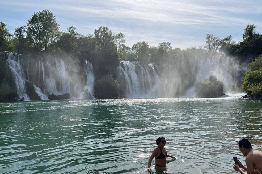 A waterfall, a woman in a bikini, and a man with a smartphone. 2