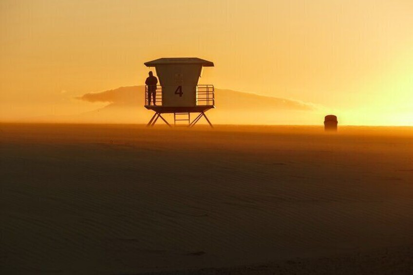 Une tour de surveillance, portant le numéro 4, surplombe une plage au coucher du soleil. 1