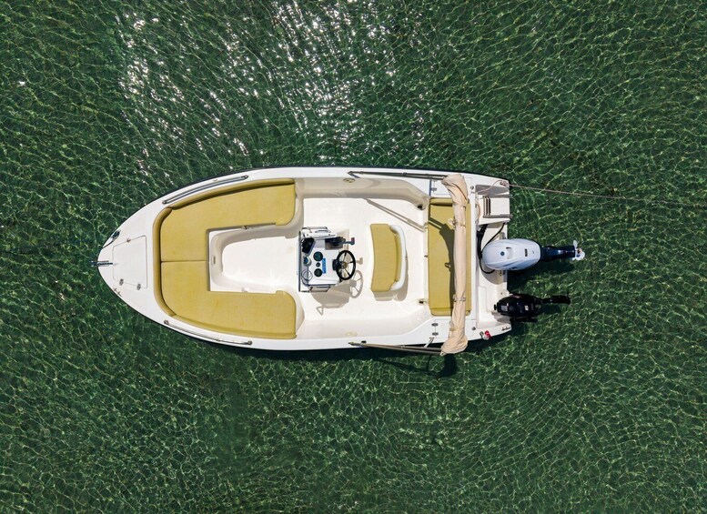 A small white boat with a yellow interior and a motor on the starboard side, floating on calm water. 4