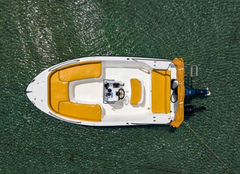 A small motorboat with yellow seating and a motor on the stern, floating on clear water. 3