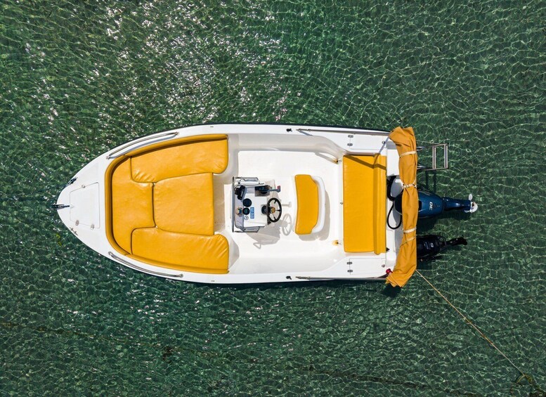 A small motorboat with yellow seating and a steering wheel, floating on clear water. 2