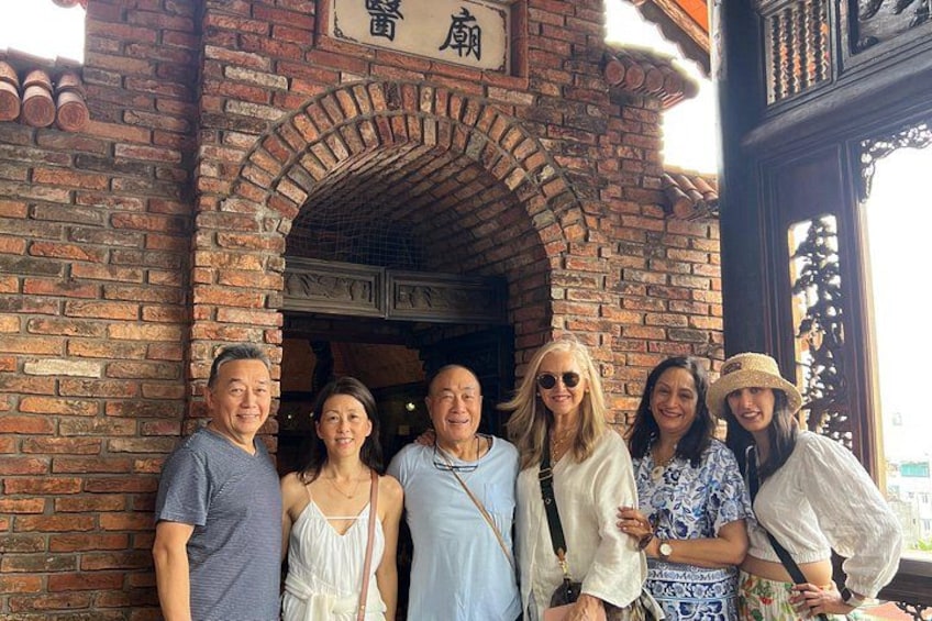 A group of people standing in front of a brick building with a sign above the entrance. 5
