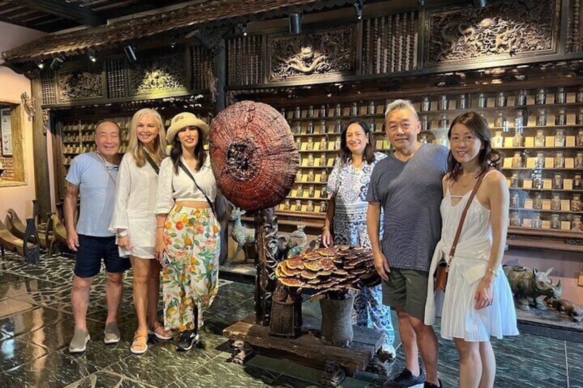 A group of people in a museum with ornate wooden carvings and a large, intricate umbrella sculpture. 2