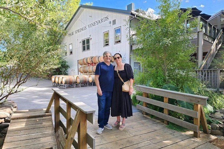A wooden bridge, a building labeled 'Page Springs Vineyards,' and barrels in the background. 4