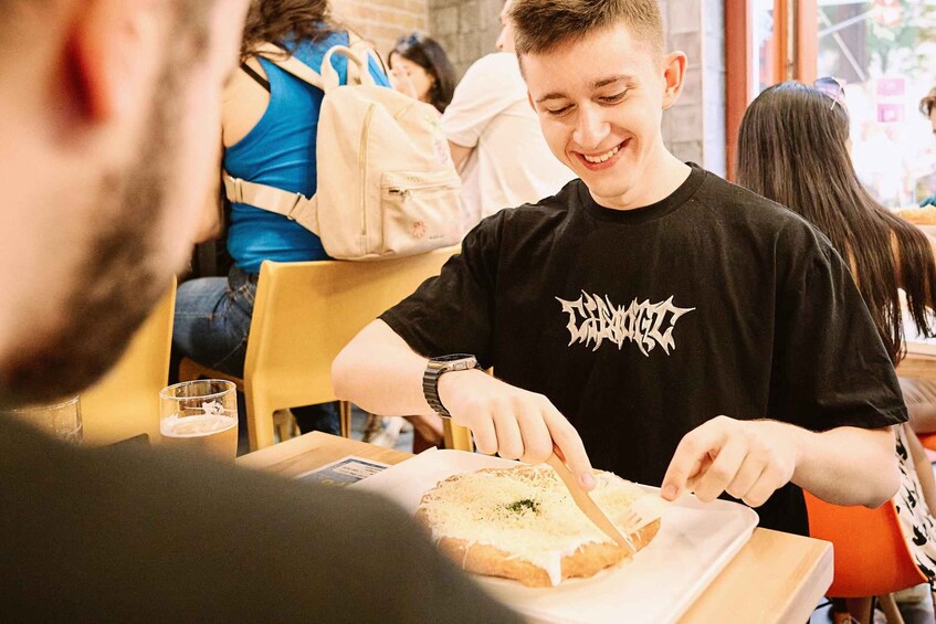 A person cutting a sandwich at a table in a cafe. 5
